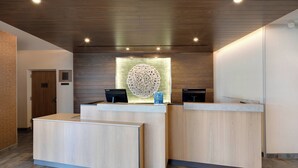 Un área de recepción con mostrador de madera, un panel de exhibición en la pared y una puerta al fondo.
