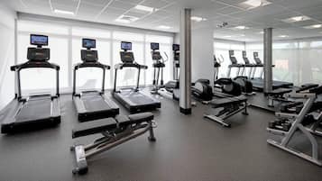 Uma academia moderna com esteiras, aparelhos de musculação e equipamentos de cardio.