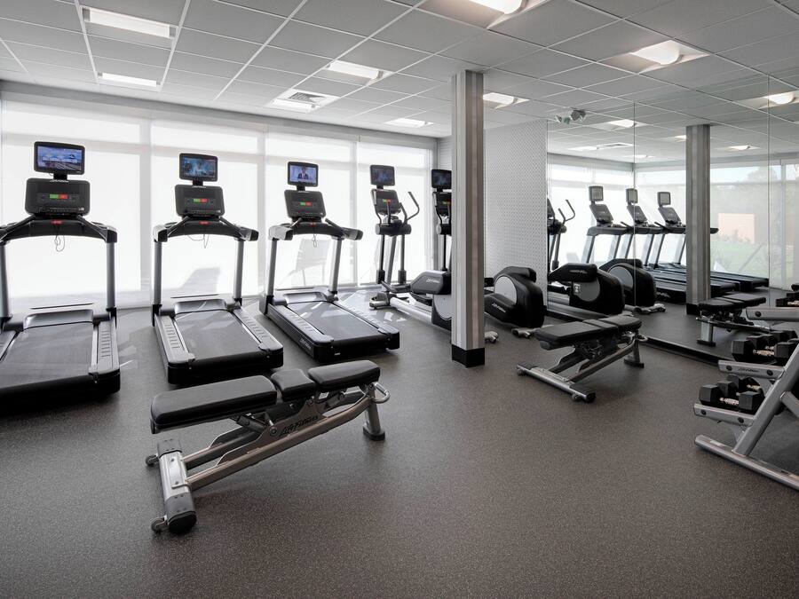 Uma academia moderna com esteiras, aparelhos de musculação e equipamentos de cardio.