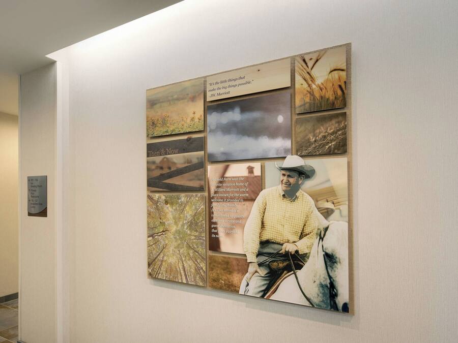 Eine Wand mit einer Collage aus Fotos und Texttafeln, darunter ein Zitat von J.W. Marriott und eine Beschreibung einer Ranch.
