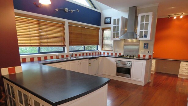 A modern kitchen with white cabinets, a black countertop, and a built-in oven. - Central Holiday House at 29 Church in Cowes (Cowes)