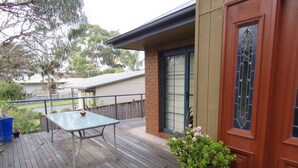 A wooden deck with a table and chairs, a potted plant, and a building with a door and windows. - Central Holiday House at 29 Church in Cowes (Cowes)