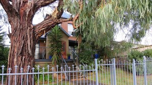 A residential property with a large tree, a fenced yard, and a house with a porch. - Central Holiday House at 29 Church in Cowes (Cowes)