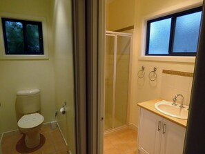 Et badeværelse med toilet, bruser og håndvask.