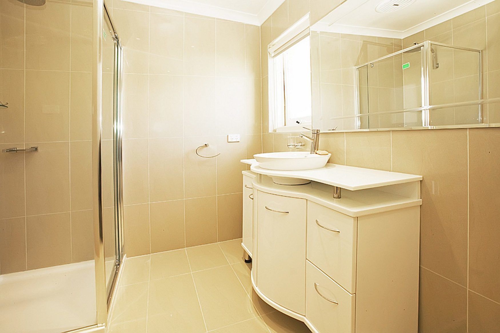 A bathroom with a bathtub, a glass shower enclosure, a sink, and a vanity with drawers.