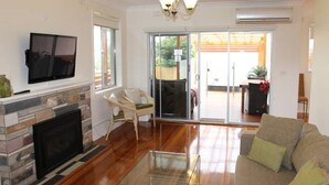 A living room with a fireplace, a flat-screen TV, a glass coffee table, and a sofa. - Island Living (Cowes)