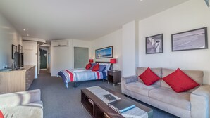 Ein modernes Hotelzimmer mit Bett, einer Couch, einem Schreibtisch und einem Fernseher.
