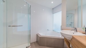 Ein modernes Badezimmer mit Duschkabine aus Glas, einer freistehenden Badewanne und einem Holzbadezimmer-Möbel mit Waschbecken.