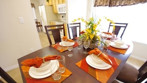 Una mesa de comedor dispuesta con platos, vasos y un centro de mesa.