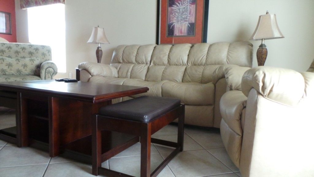 A living room with a beige leather sofa, a wooden coffee table, and two lamps.