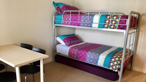 A bunk bed with colorful bedding, a small table, and two chairs. - The Waves 216 (Cowes)