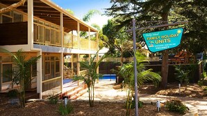 A two-story building with a covered porch and a sign advertising family holiday units. - Beach House Units - 1 (Cowes)