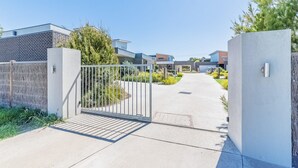 A gated entrance to a residential area with modern houses, a clear sky, and a paved pathway. - Birch Holiday House (Cowes)
