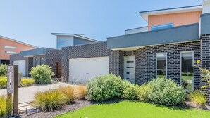 A modern two-story house with a garage, surrounded by well-maintained landscaping and a clear sky. - Birch Holiday House (Cowes)