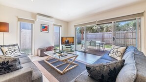 A spacious living room with a glass coffee table, a sofa, and a television. - Birch Holiday House (Cowes)