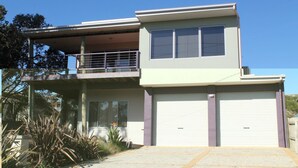 A two-story house with a balcony, large windows, and a garage. - 61 Redrocks Retreat (Cowes)