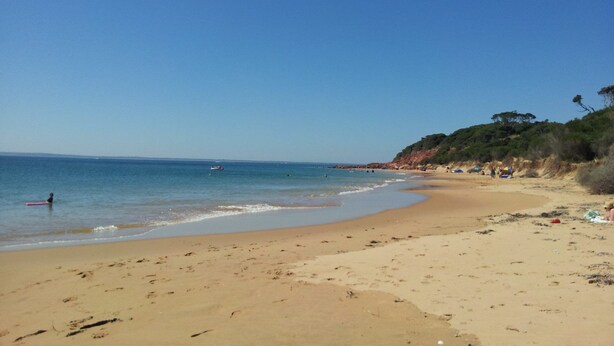 A sandy beach with clear blue water, a few people, and some boats in the distance. - 61 Redrocks Retreat (Cowes)