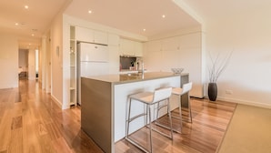 A modern kitchen with a central island, bar stools, and a refrigerator. - C-Scape by the Sea No.9 (Cowes)