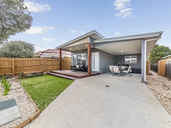A modern house with a covered patio, a small backyard, and a wooden fence. - Genesta 5B House in Cowes (Cowes)