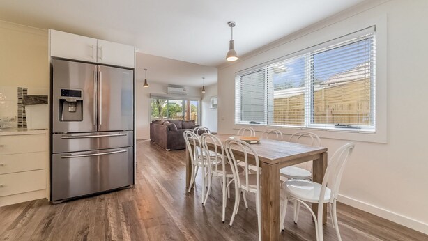 A modern kitchen with a stainless steel refrigerator, a built-in water dispenser, and a dining area with a wooden table and white chairs. - Genesta 5B House in Cowes (Cowes)