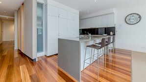 Een moderne keuken met een centraal eiland, barstoelen en een klok aan de muur.