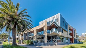 Een modern gebouw met een uniek architectonisch ontwerp, inclusief een opvallende trap en een café op de begane grond.