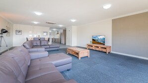 A modern living room with a sectional sofa, a coffee table, and a TV on a wooden stand. - Thompson Avenue Apartments No.1 (Cowes)