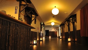A hallway with wooden paneling, recessed lighting, and a wooden staircase. - Yadoya Tsubaki (Aomori)