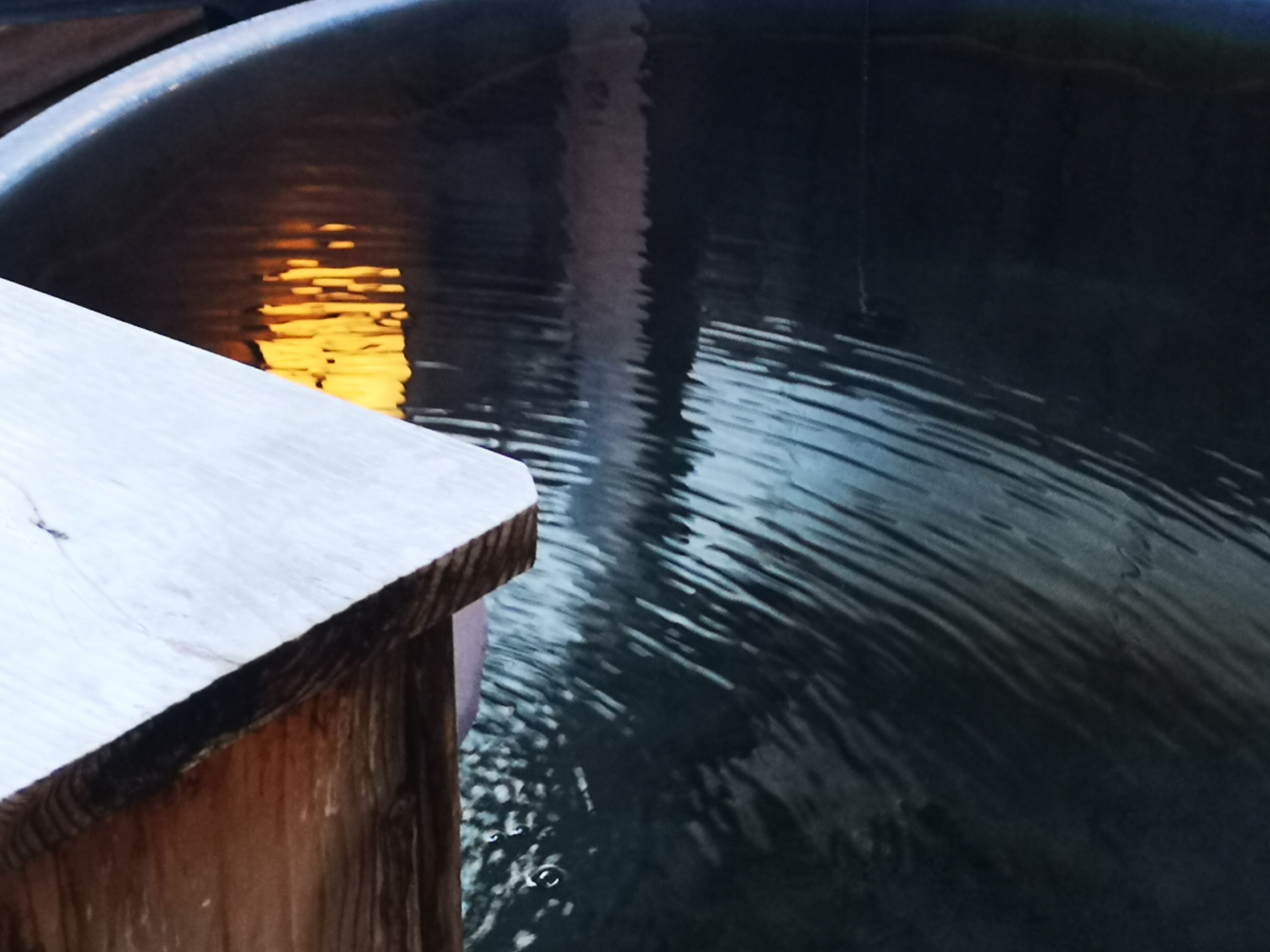 Une surface en bois se reflétant sur une étendue d’eau sombre.