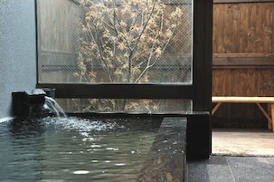 Una fuente de agua moderna en el interior, con vista clara a un árbol a través de una ventana.