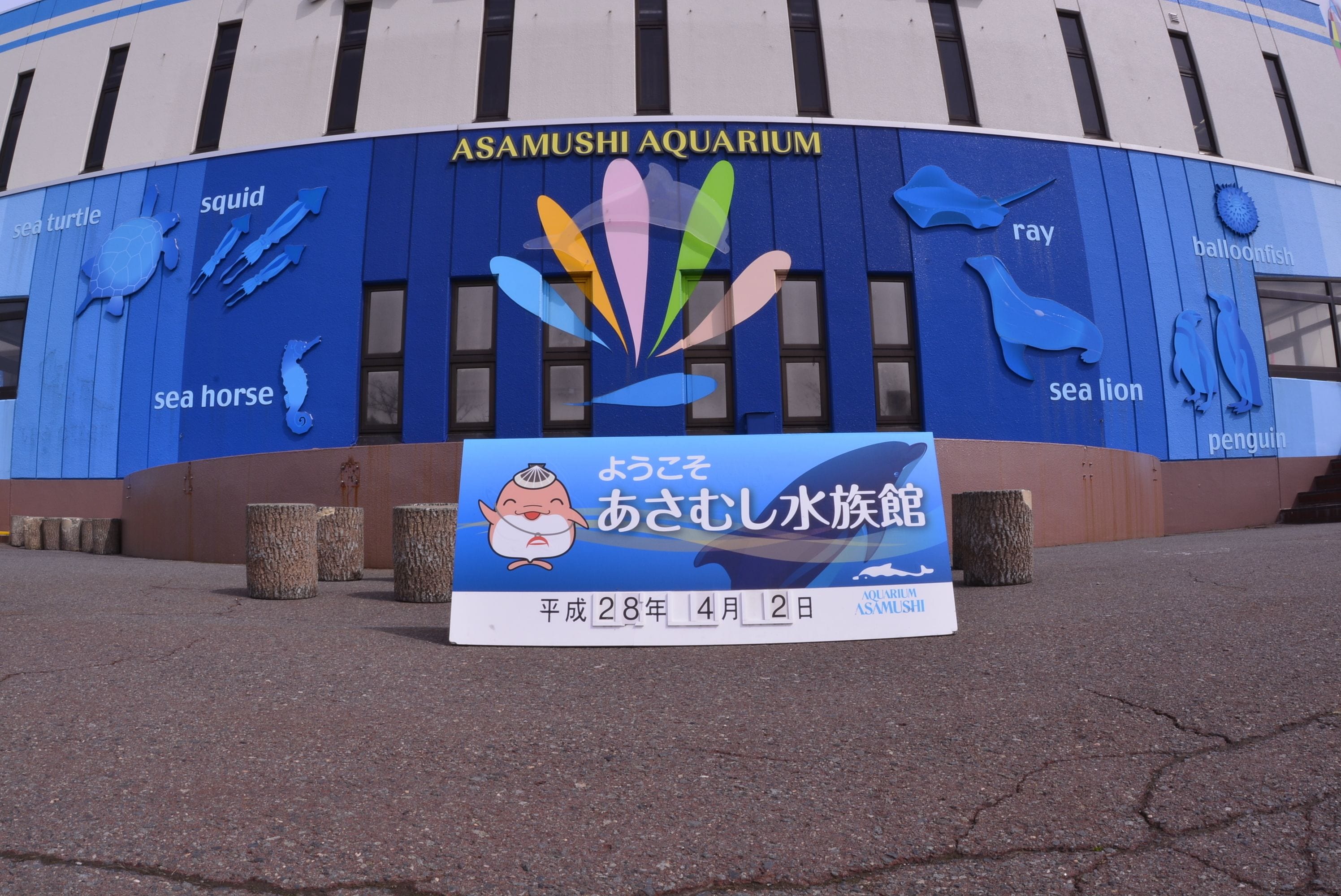 Exterior del Acuario de Asamushi con señalización de tortugas marinas, calamares, caballitos de mar, rayas, lobos marinos y pingüinos.