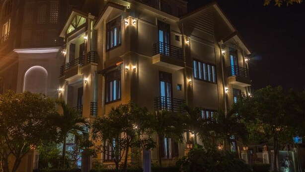 A multi-story building with balconies, illuminated windows, and a well-maintained garden area. - Lantern Villa (Da Nang)