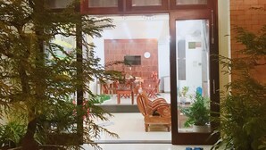 A hotel entrance with a tiled floor, a potted plant, a wooden bench, and a view into the dining area. - Lantern Villa (Da Nang)