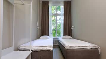 A twin bedroom with two single beds, a window with curtains, and a radiator.
