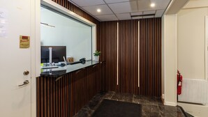 A modern reception area with a wooden panel wall, a reception desk, a large mirror, and a fire extinguisher. - Vandrarhem Lidköping - Hostel (Lidköping)