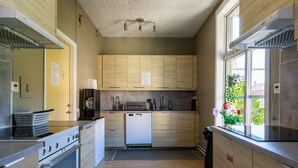 A modern kitchen with wooden cabinets, a dishwasher, and a stove. - Vandrarhem Lidköping - Hostel (Lidköping)
