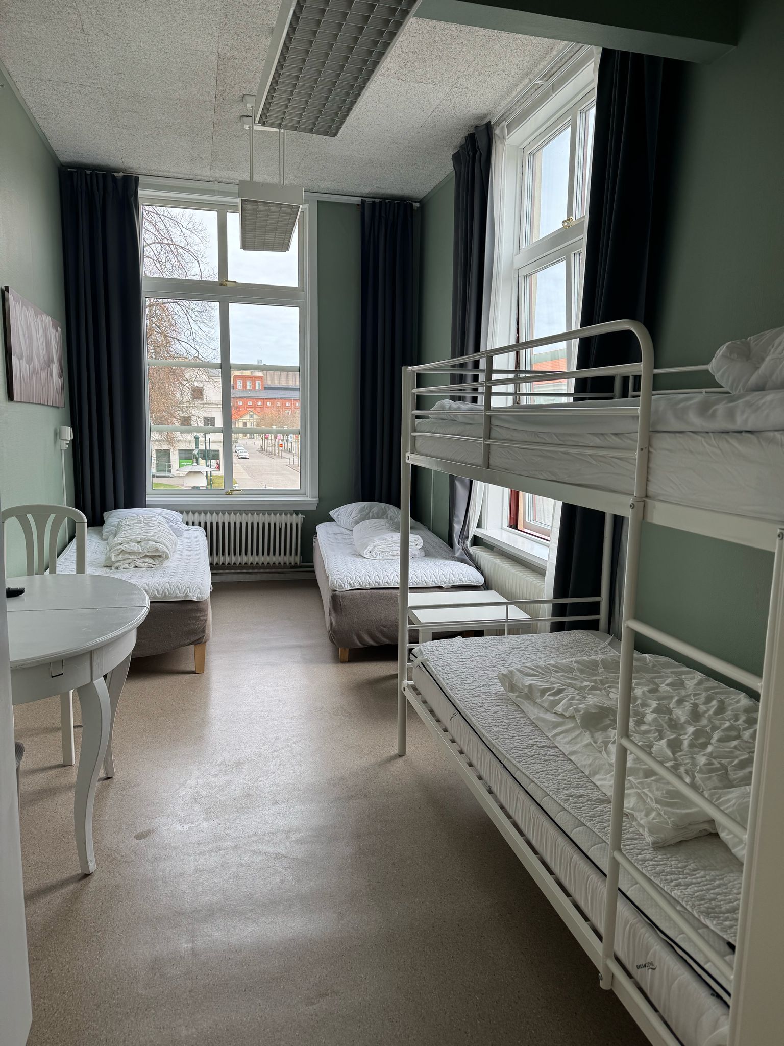Ett sovsalsrum med våningssängar, ett litet bord och en stol.