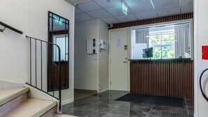 A hotel lobby with a staircase, reception desk, and a view of the outdoors. - Vandrarhem Lidköping - Hostel (Lidköping)