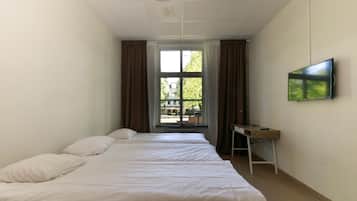 Ett hotellrum med två sängar, ett skrivbord och en tv på väggen.