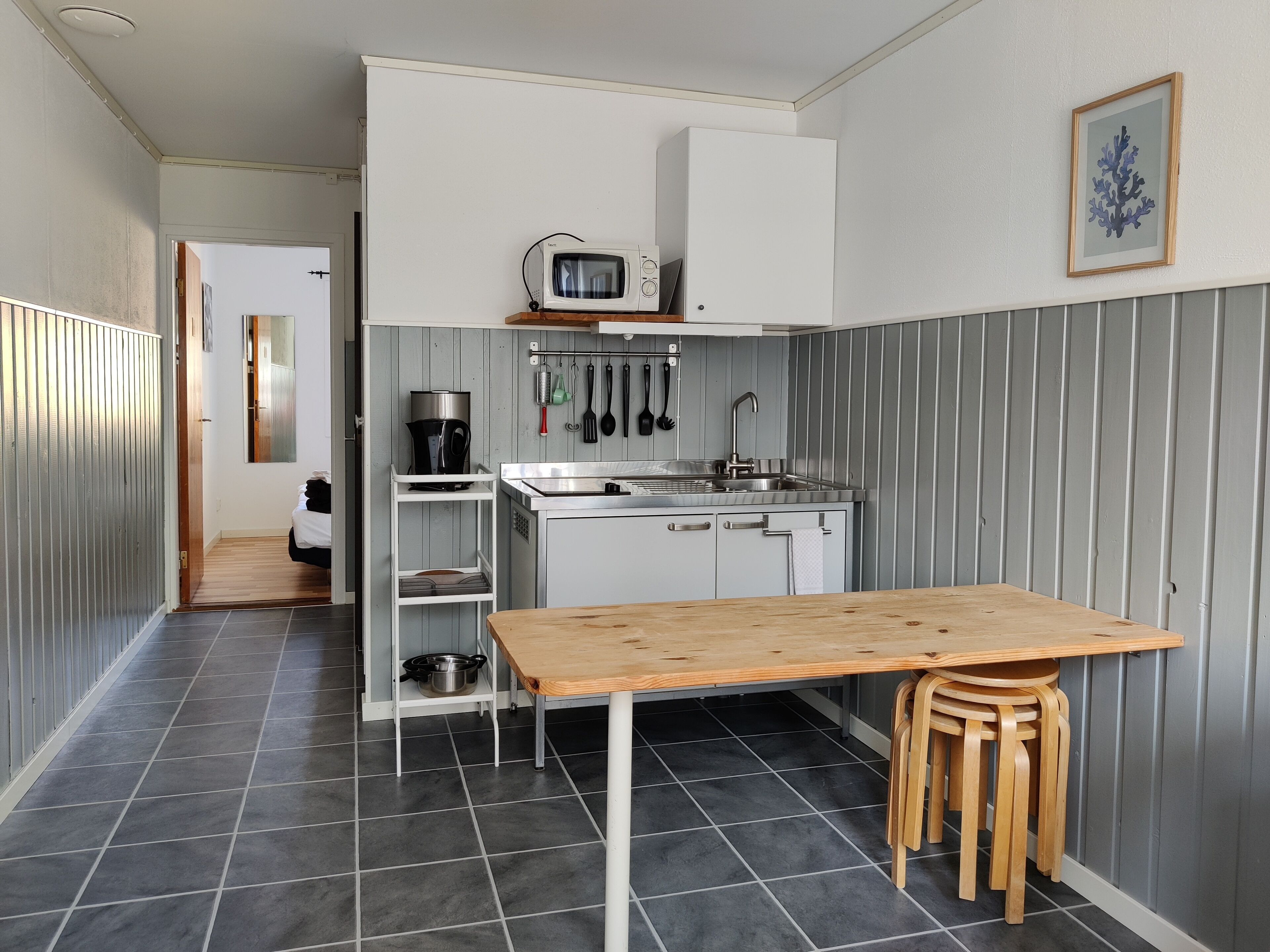 Una cocina compacta con una mesa y sillas de madera, un microondas y un lavamanos.