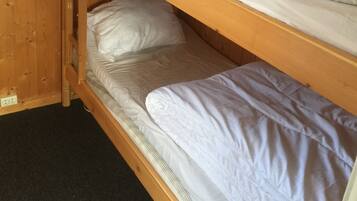 A bunk bed with white bedding in a wooden room.