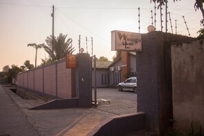Une entrée fermée par un portail, avec une enseigne indiquant « The Wasingo West Inn » et une enseigne Airtel.