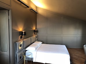 Una camera da letto con un letto, due lampade a parete, un comodino e una porta.