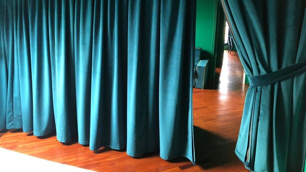 Quarto com parede verde e piso de madeira, com cortinas verde-água.