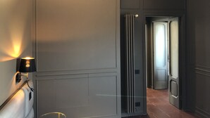 Um corredor com uma porta moderna, uma luminária na parede e um radiador.