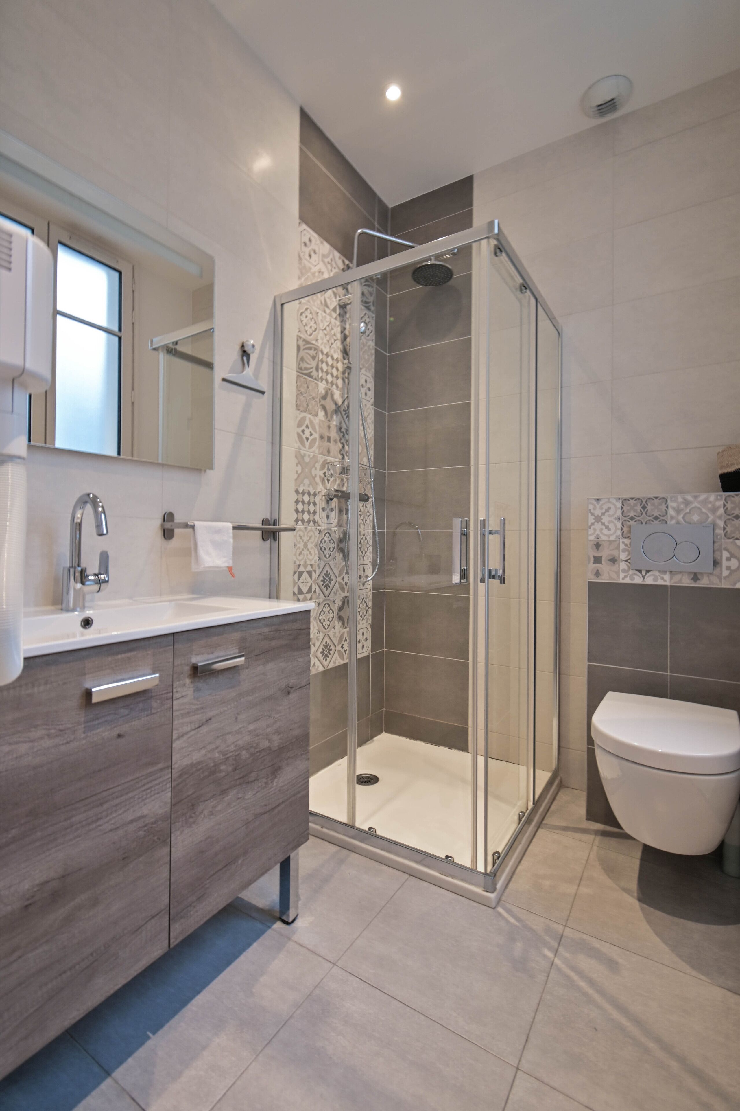 A modern bathroom with a glass-enclosed shower, a vanity with a mirror, and a toilet.