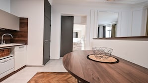 Una cocina moderna con armarios blancos, una mesa de comedor de madera y suelo con un patrón de espiga.