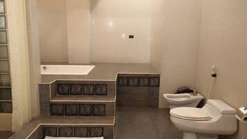 A bathroom with a bathtub, toilet, and a shower area.