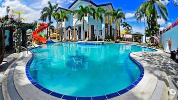 Relax by the pool surrounded by palm trees and lounge chairs.