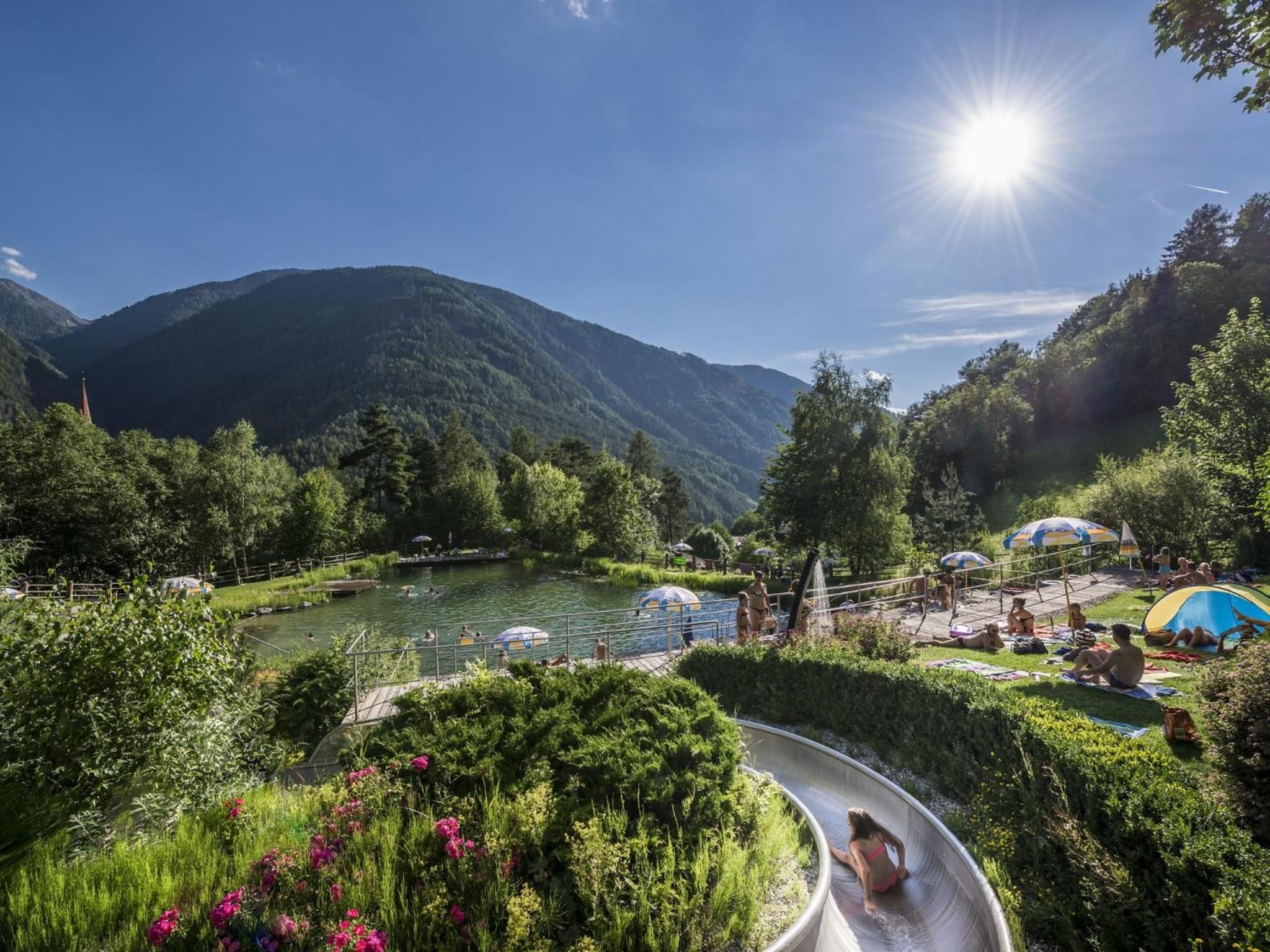 A water slide in a lush, mountainous area with a clear sky.
